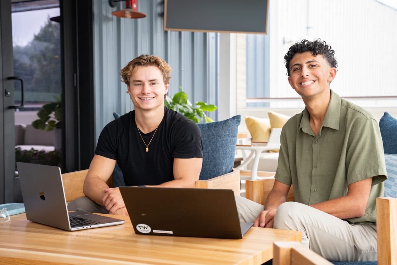 Evan Camire and Aaron Gallo sitting at a table with their laptops